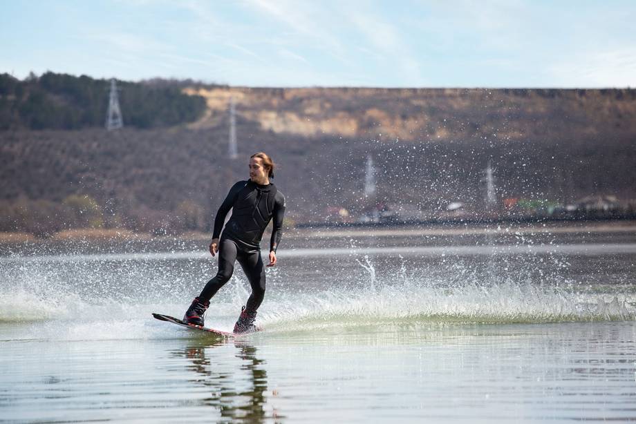 Wakeboarder in action on a calm lake with forested hills in background