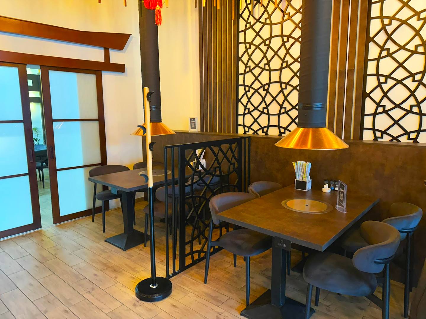 Modern café interior with wooden tables, geometric screen dividers, and warm lighting