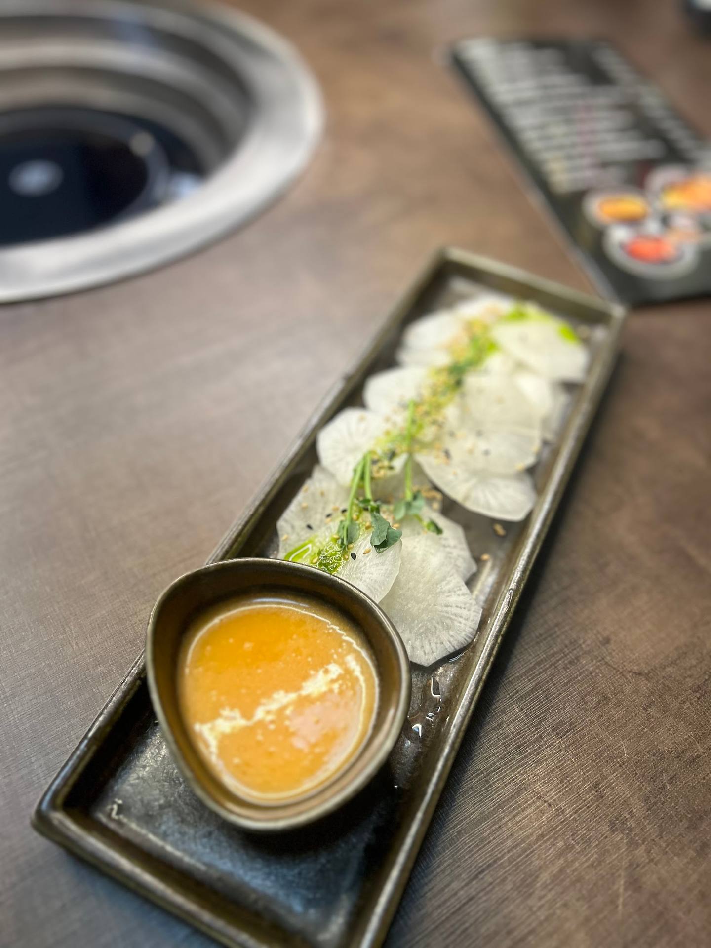 Sliced fish or seafood platter with dipping sauce and remote control visible
