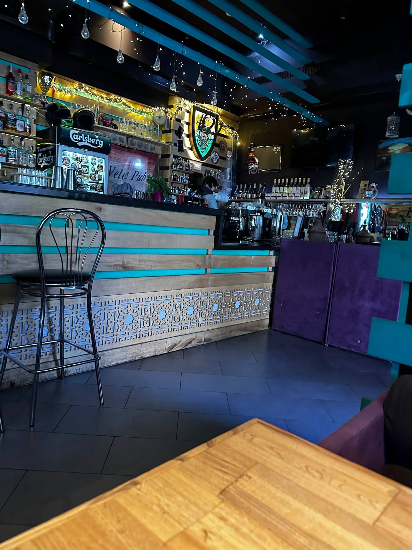Colorful modern bar interior with turquoise accents, striped counter, and craft beer signage