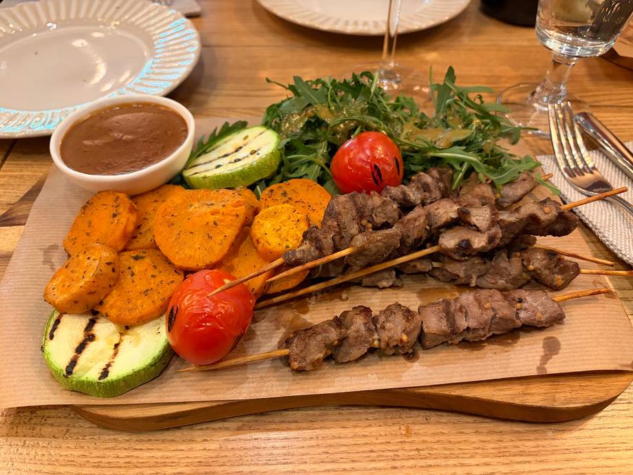 Grilled meat and vegetable platter with dipping sauce on wooden board