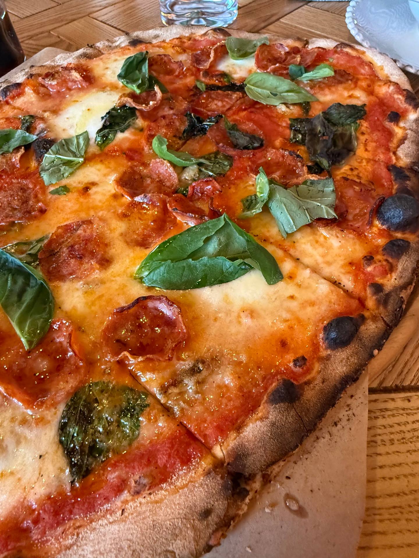 Margherita pizza with fresh basil on wooden serving board