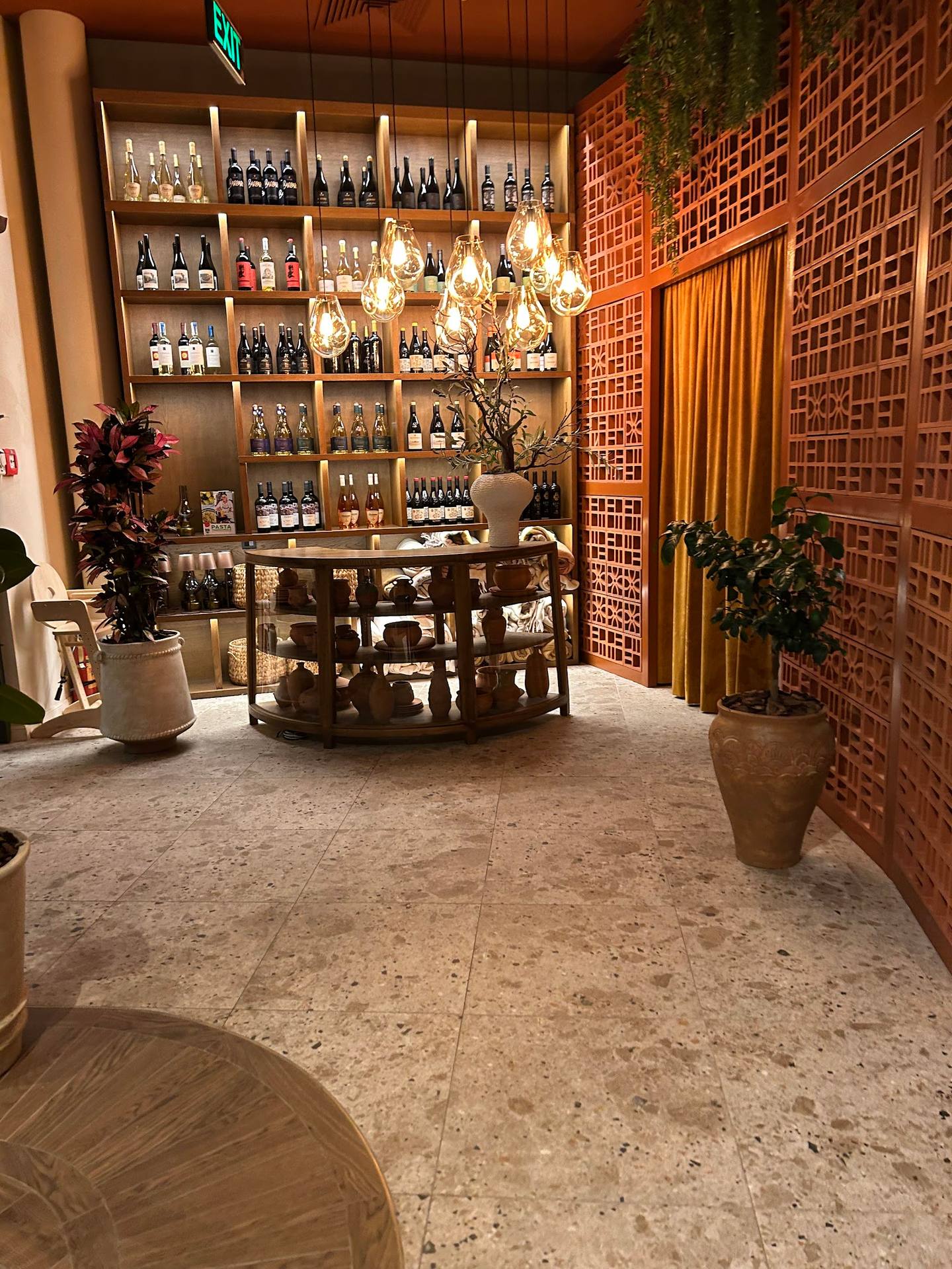 Modern wine bar interior with central tasting table and floor-to-ceiling bottle display