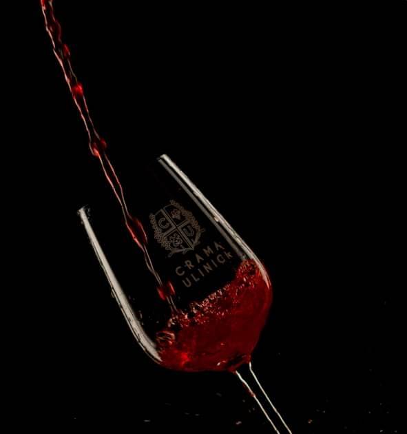 Red wine poured into glass with visible label on black background