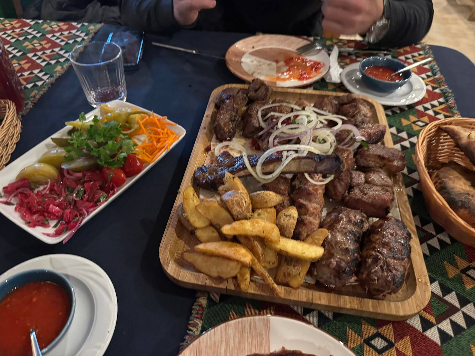Grilled meat platter with fries and fresh appetizers at table
