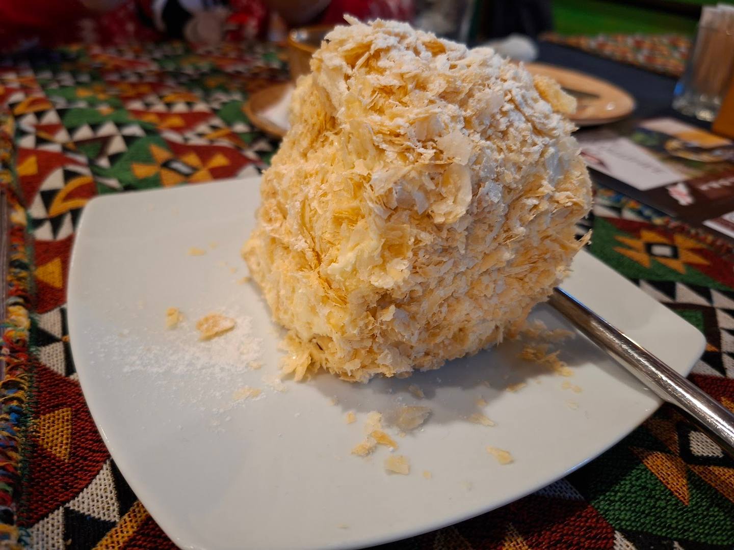 Layered cream dessert with textured frosting on white plate