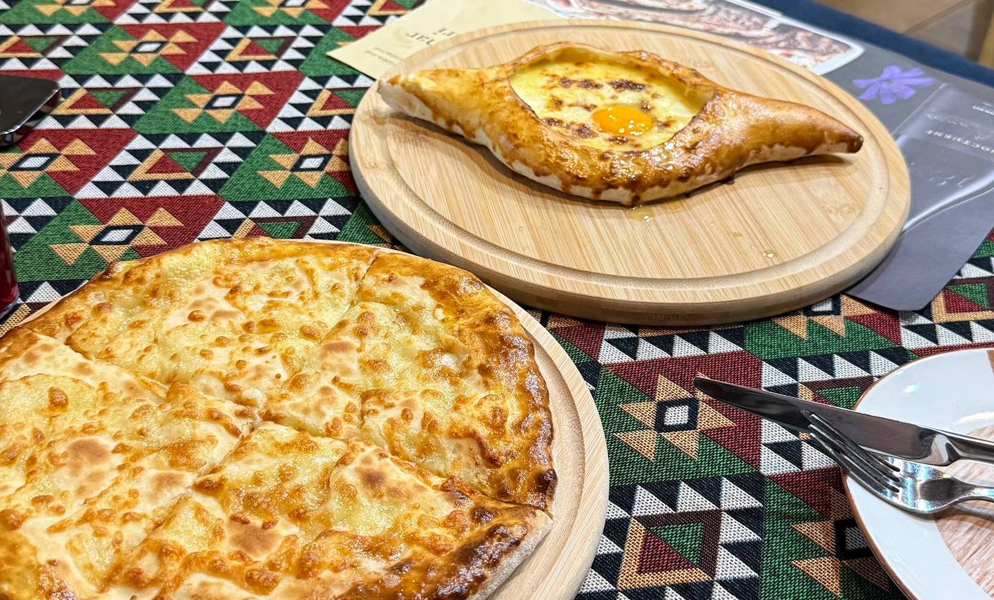 Traditional pastries and khachapuri served on wooden plates with patterned tablecloth