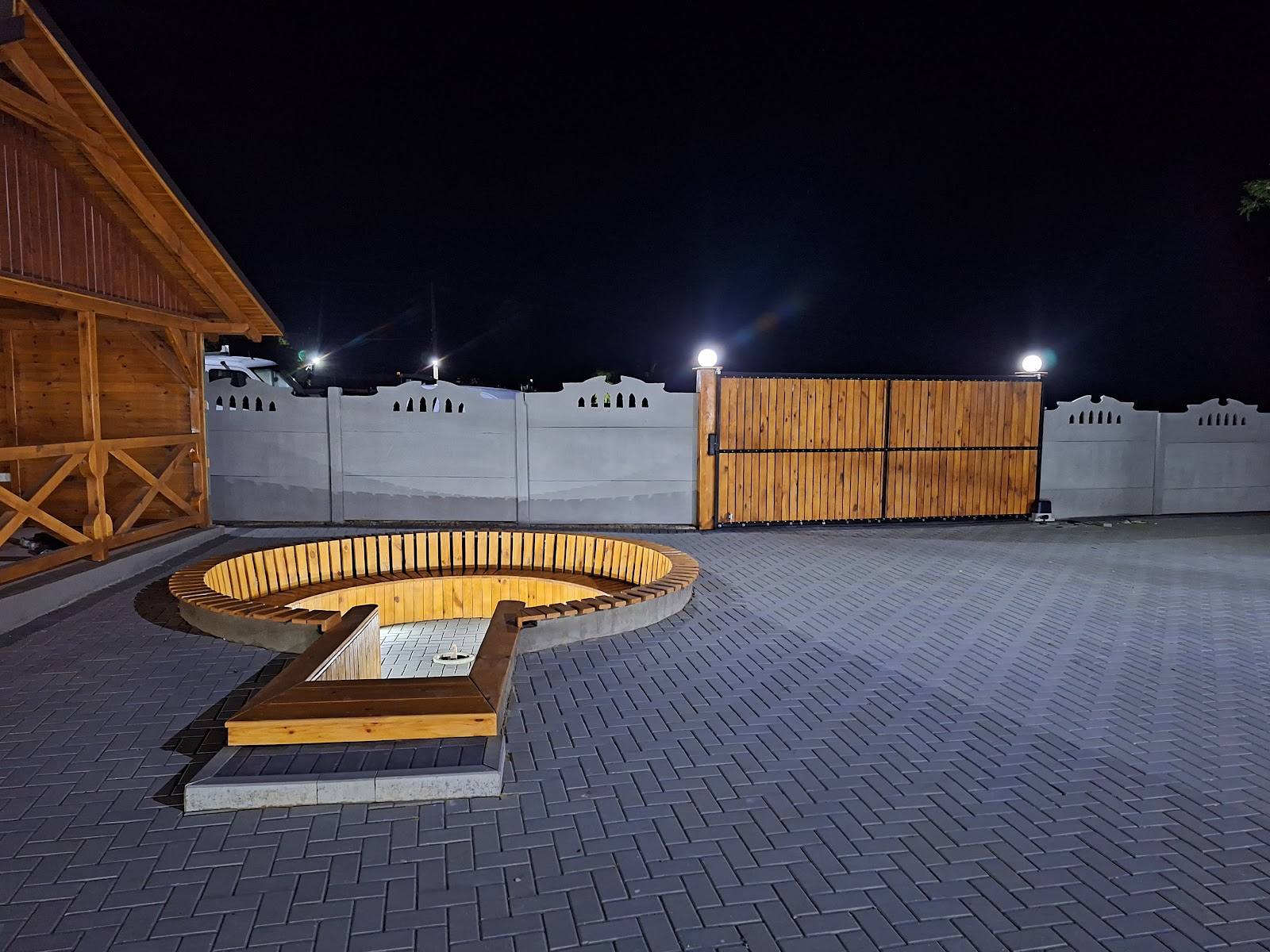 Illuminated outdoor terrace with circular seating and wooden farmhouse architecture at night