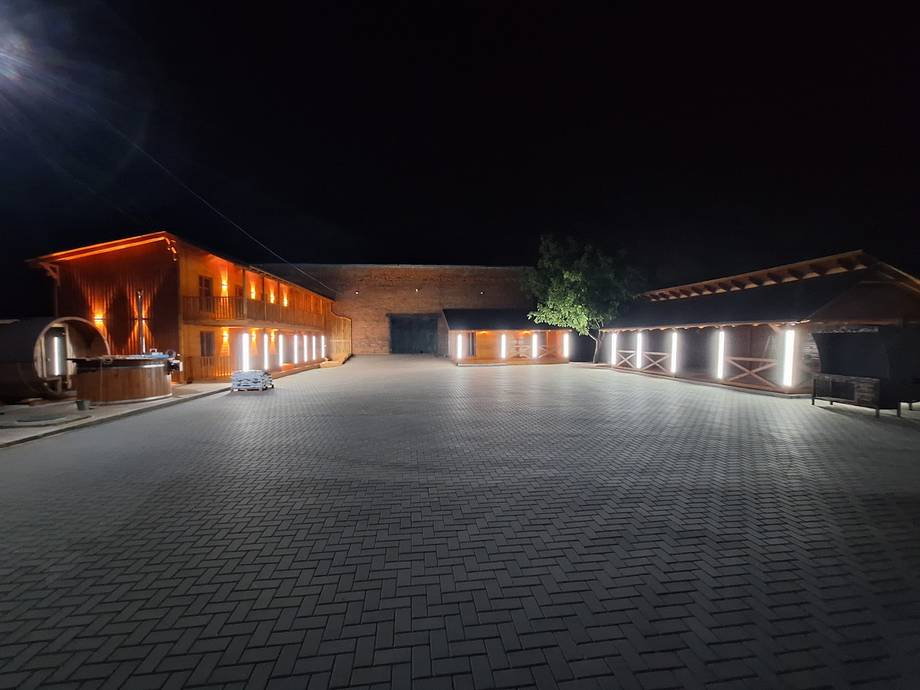 Modern brick venue building with warm exterior lighting and spacious paved courtyard at night