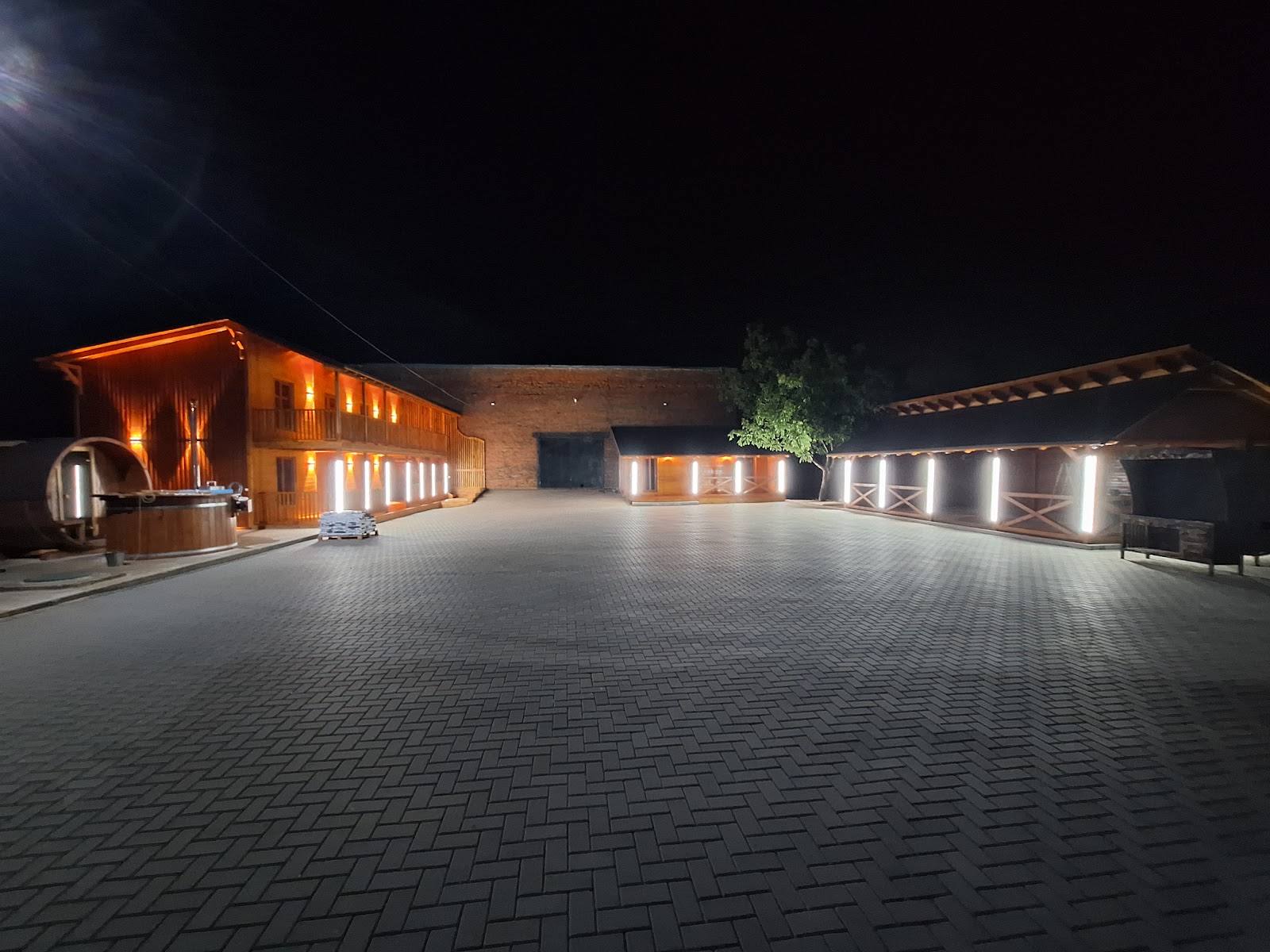Modern brick venue building with warm exterior lighting and spacious paved courtyard at night