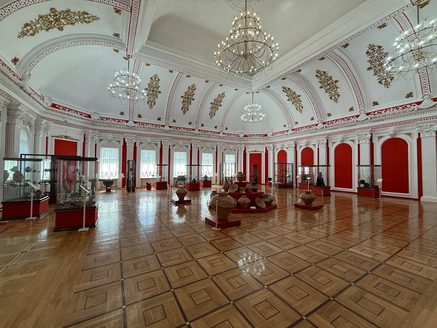 Grand ballroom with red accents, crystal chandeliers, and ornate ceiling details
