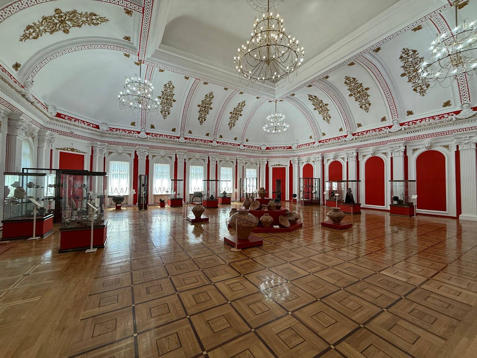 Grand ballroom with red accents, crystal chandeliers, and ornate ceiling details