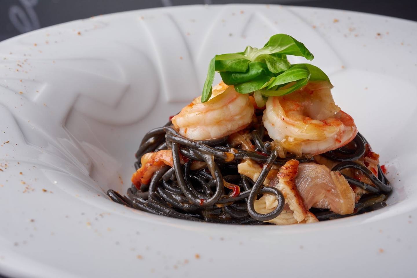 Black squid ink pasta with seared shrimp and basil garnish