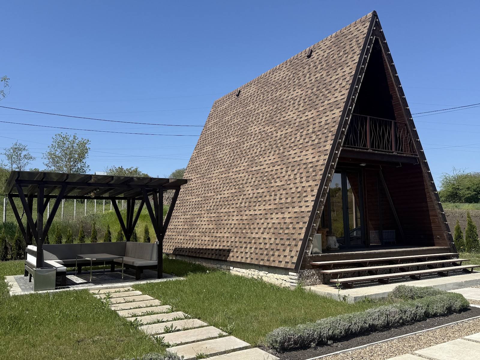 Modern monastery chapel with steep pitched roof and wooden entrance, set in rural Moldova landscape