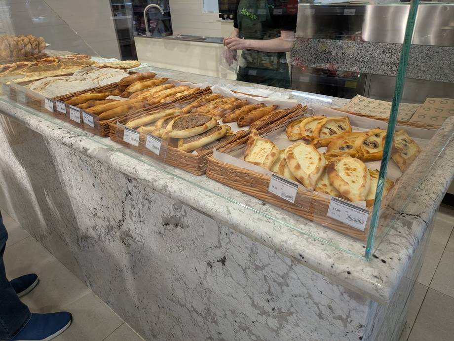 Assorted pastries and baked goods in display case with customer visible