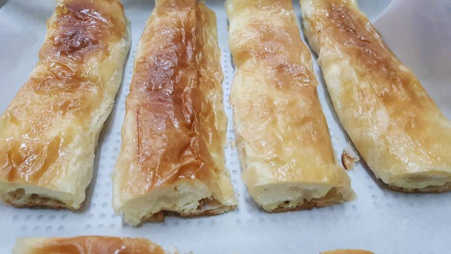 Four pastry rolls with golden-brown phyllo pastry, professionally plated