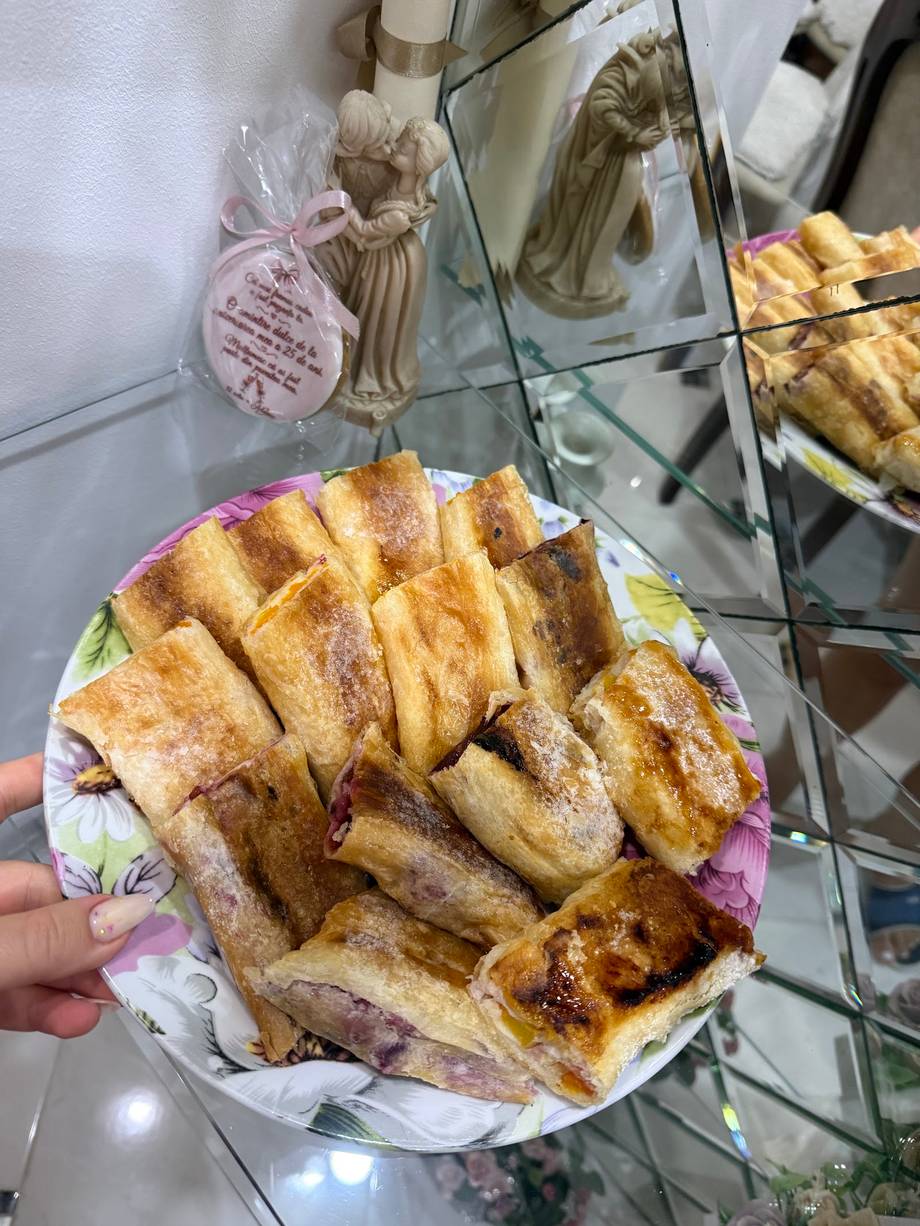 Golden-baked pastry slices arranged on decorative plate with religious figurines visible in background