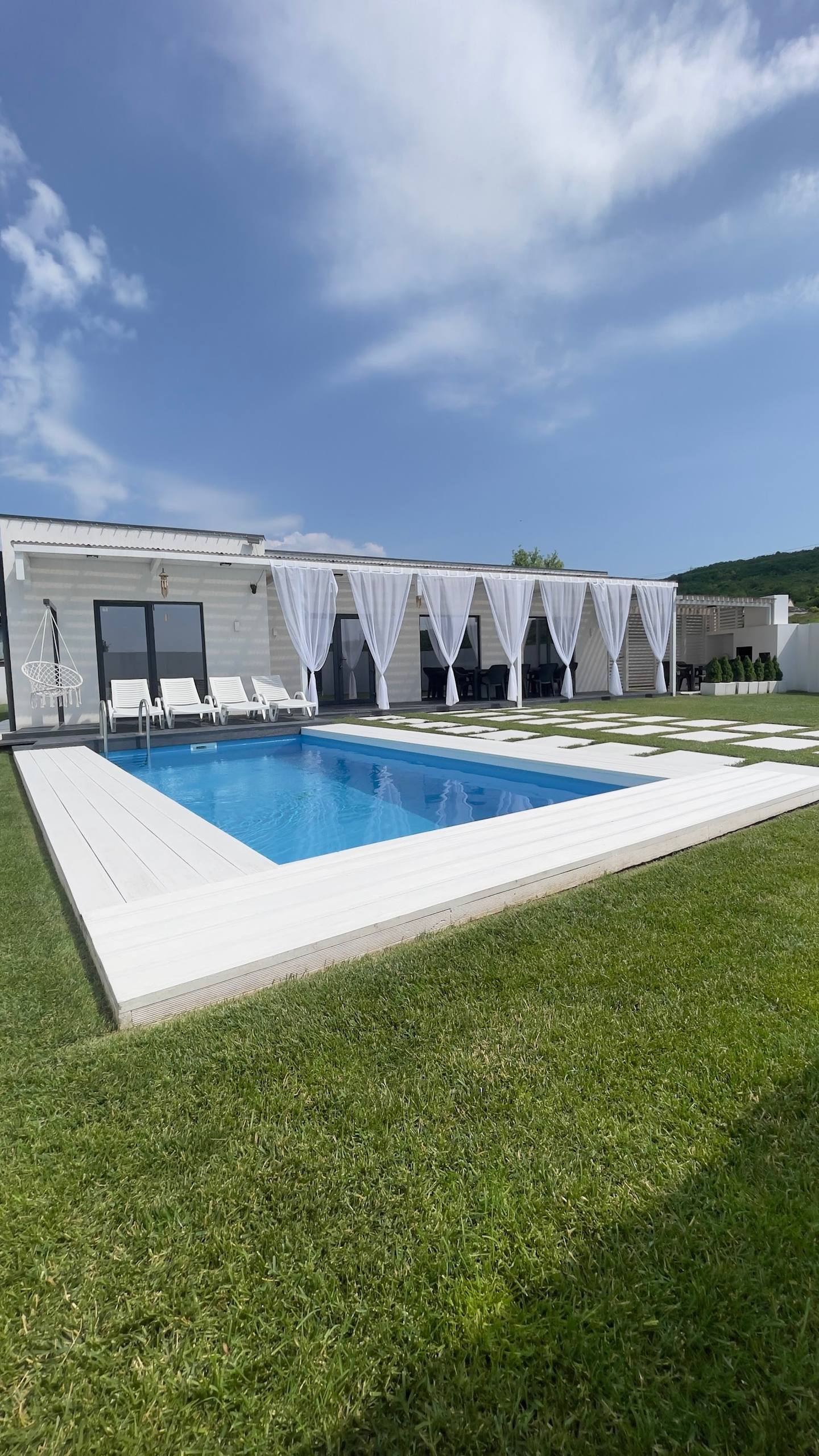 Modern pool and spa facility with white architecture, lounge seating, and landscaped grounds