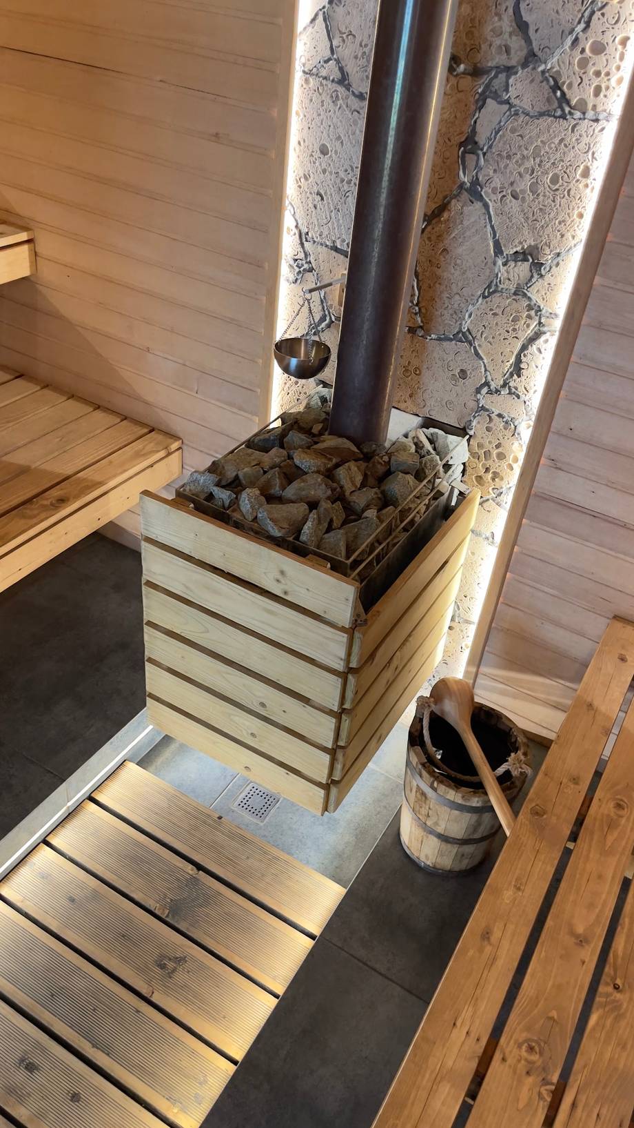 Wooden sauna stove with stone base and metal pipe in relaxation area