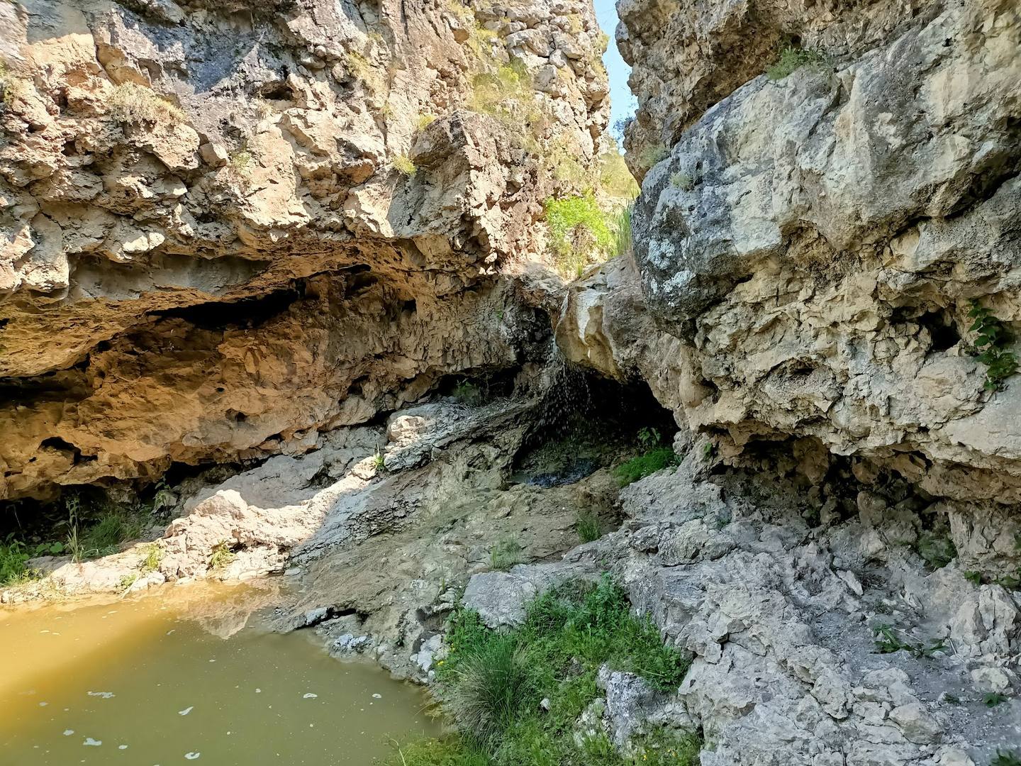 Natural limestone cave with waterfall and pond in Moldovan gorge
