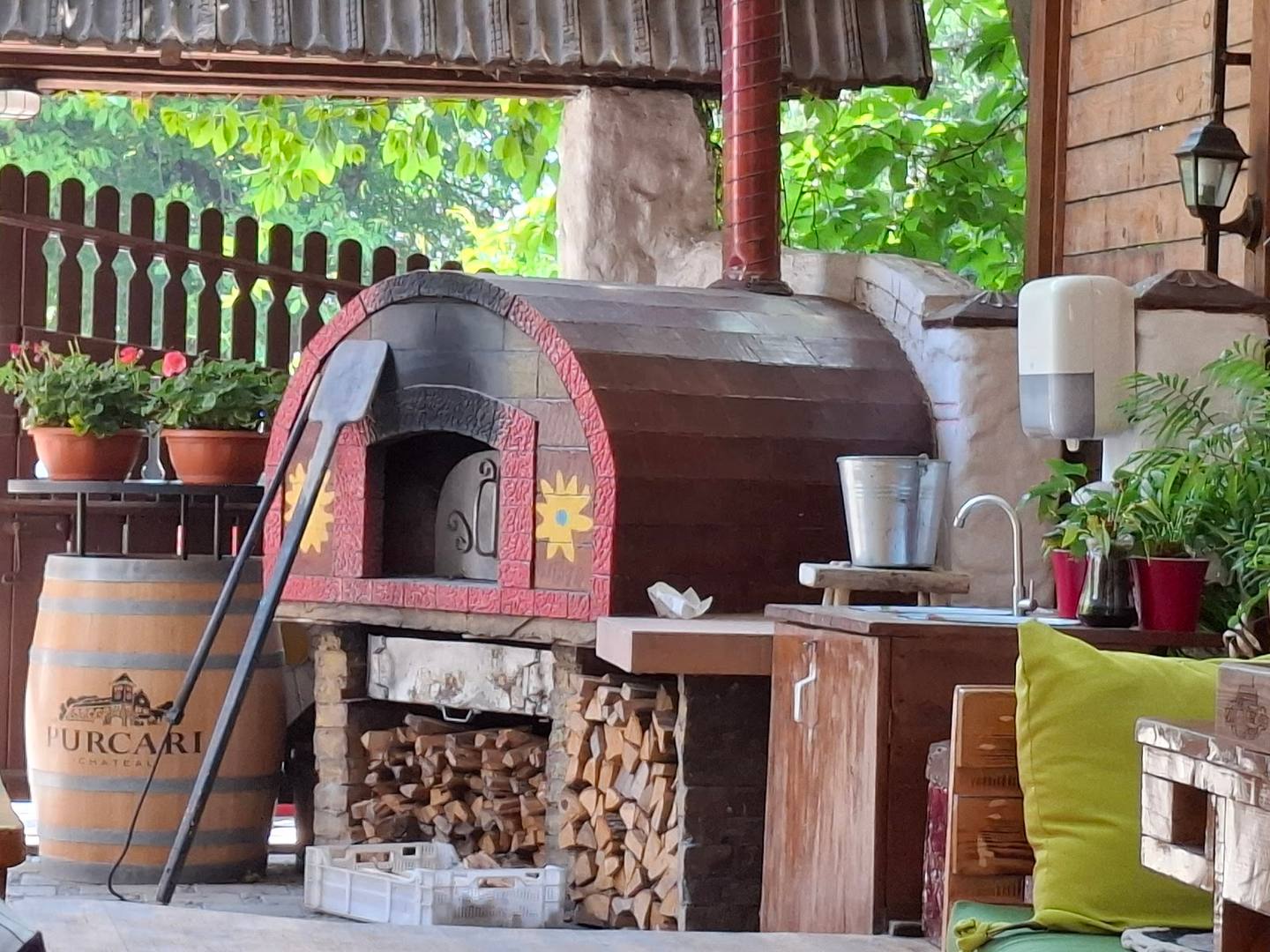 Wood-fired pizza oven on covered terrace with rustic outdoor seating area