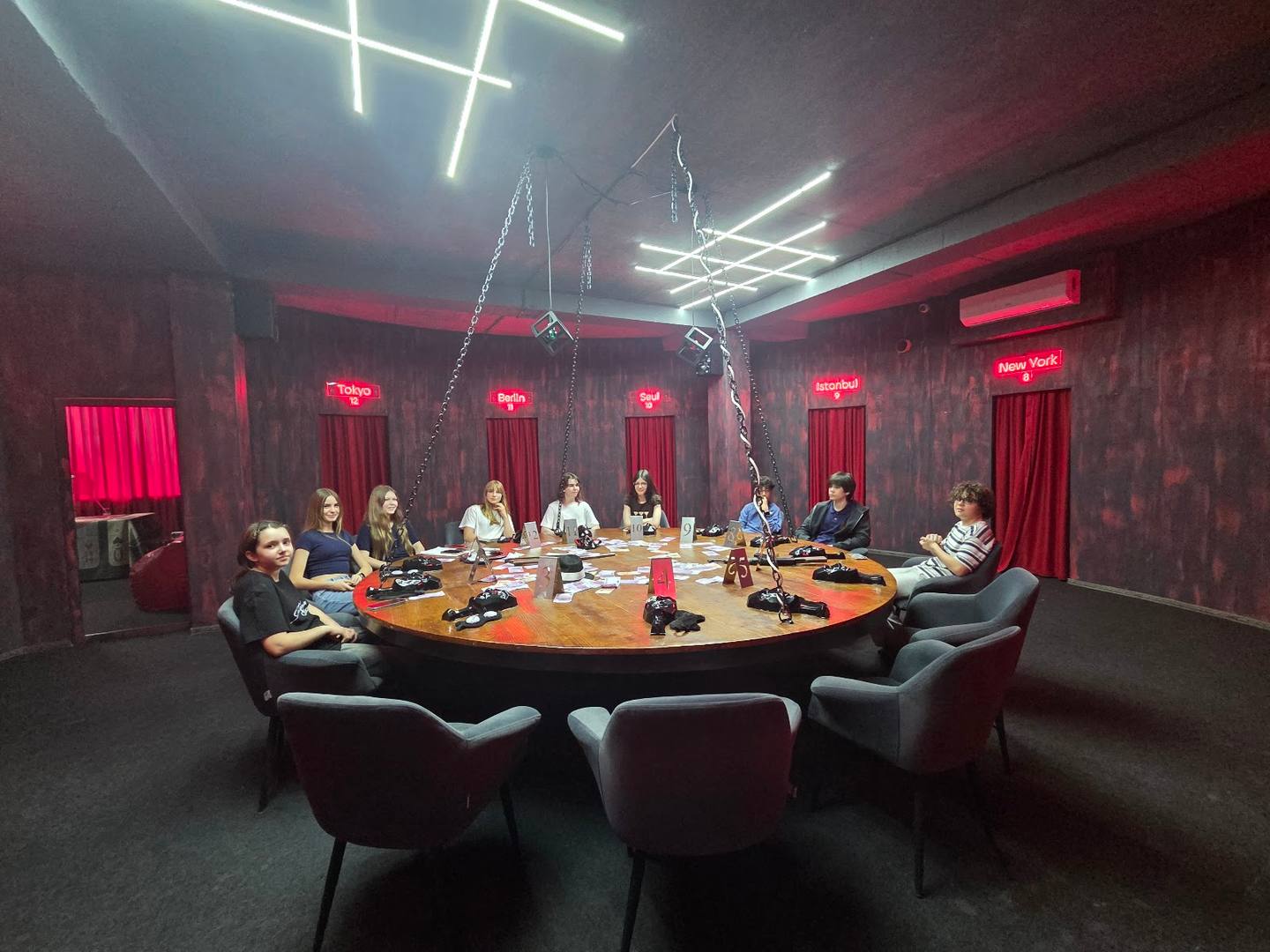 Modern private dining room with circular table, dramatic red ambient lighting, and geometric ceiling design