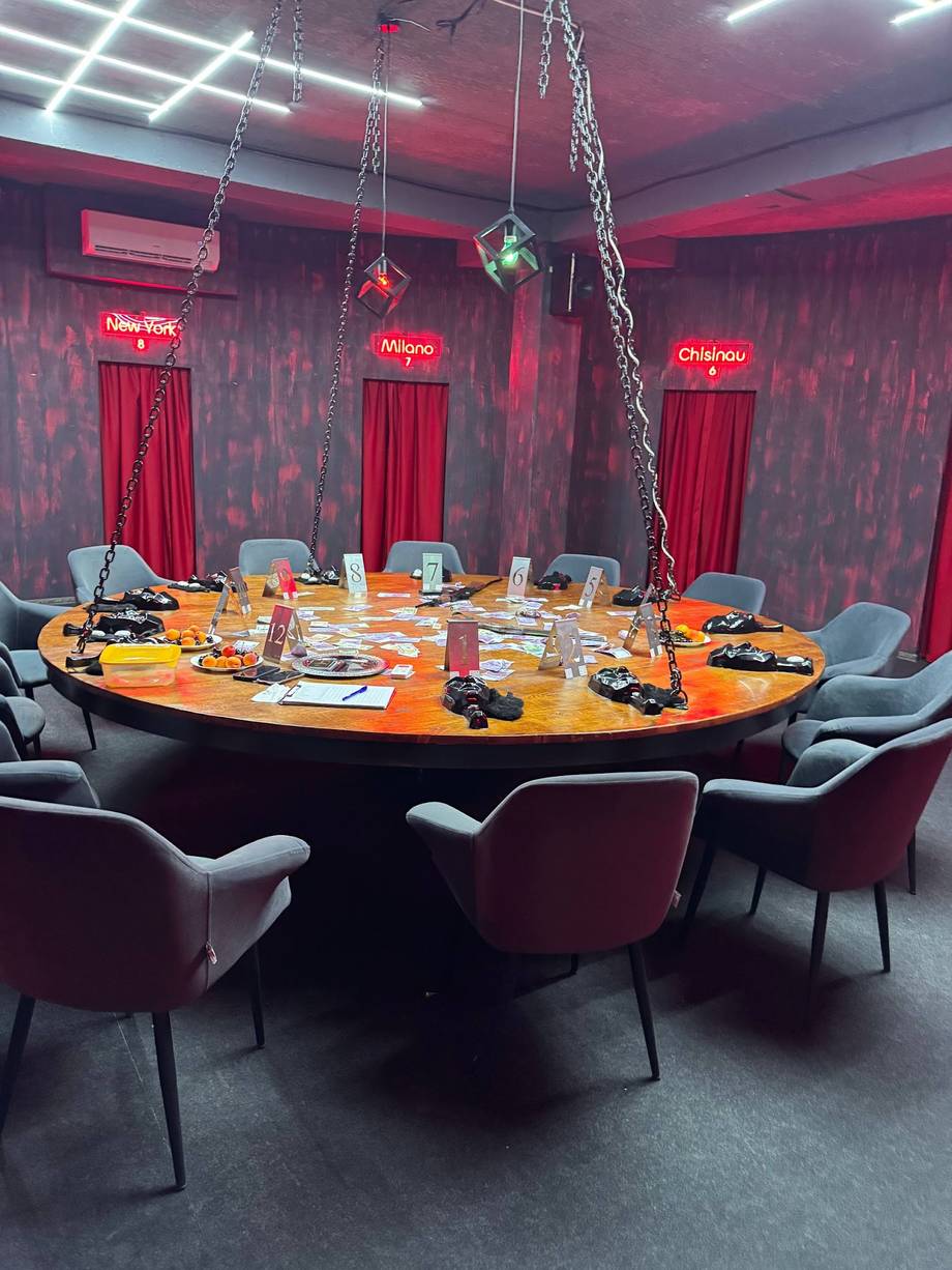 Modern private dining room with round table, red and pink ambient lighting, and contemporary décor
