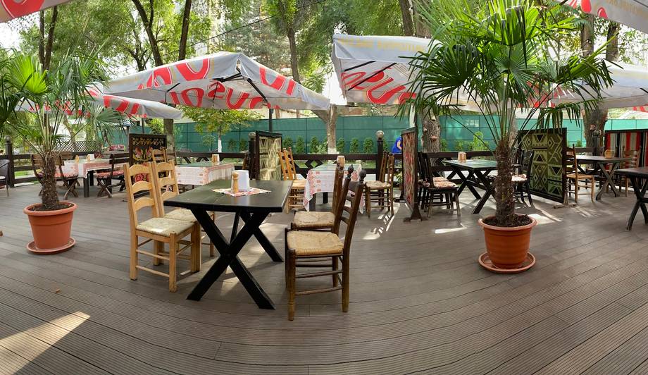 Outdoor terrace with shade umbrellas, wooden tables, and lush greenery