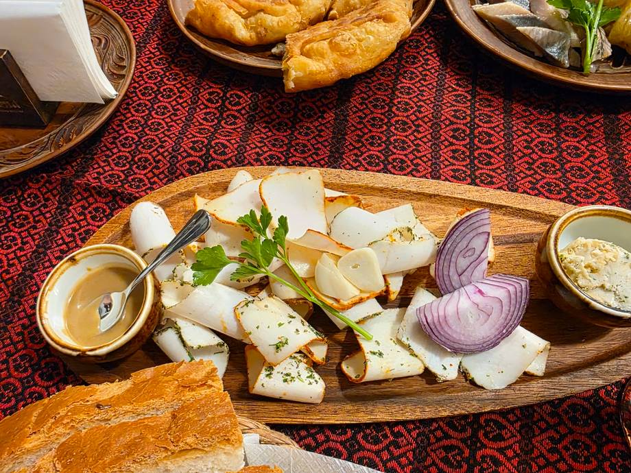 Cheese and charcuterie board with fresh vegetables and dips on decorative textile