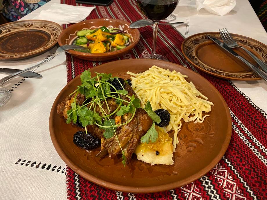 Plated main course with meat, noodles, and seasonal vegetables on ceramic tableware