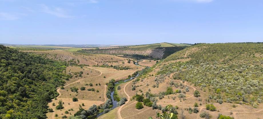 Panoramic aerial view of Moldovan landscape with winding river valley and forested hills