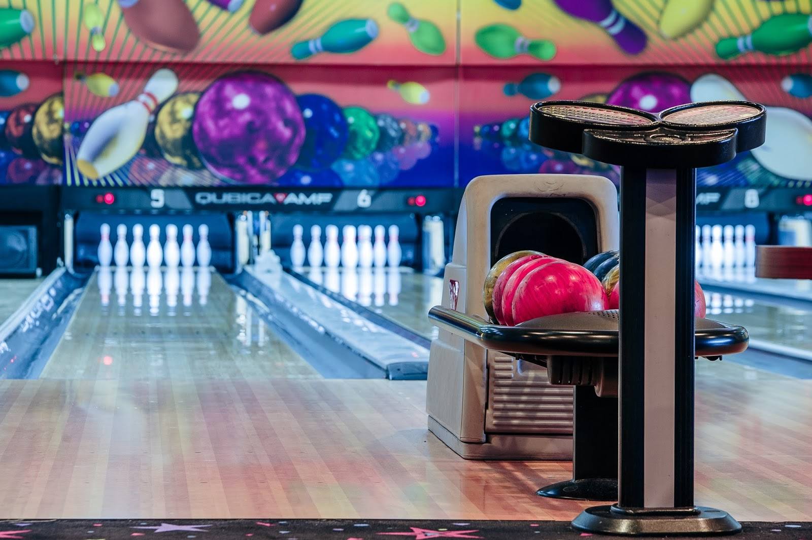 Bowling lane with colorful ball dispenser and lanes receding into distance