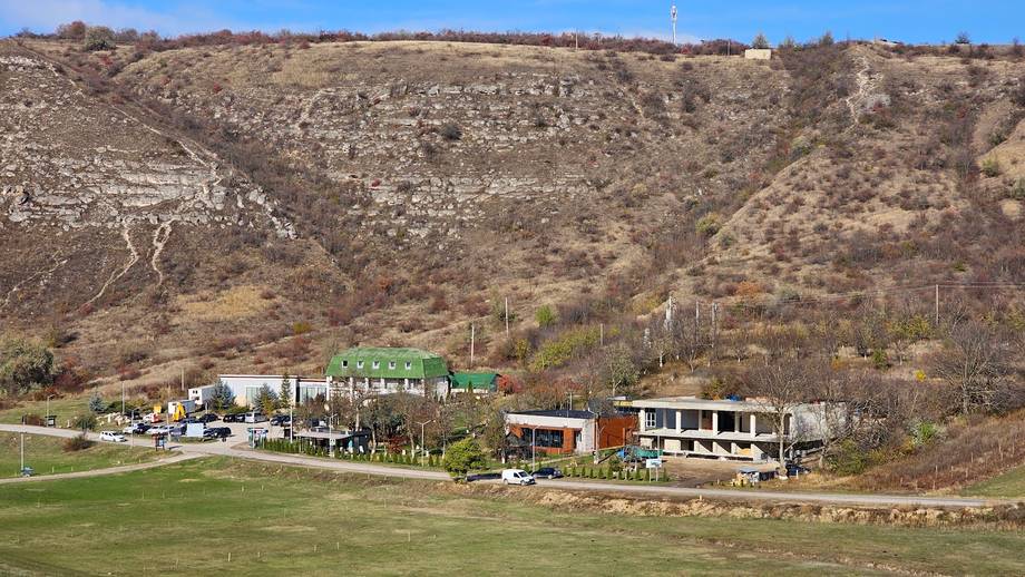 Rural winery or agritourism venue nestled at the foot of vineyard-covered hillside with guest buildings and terraced grounds