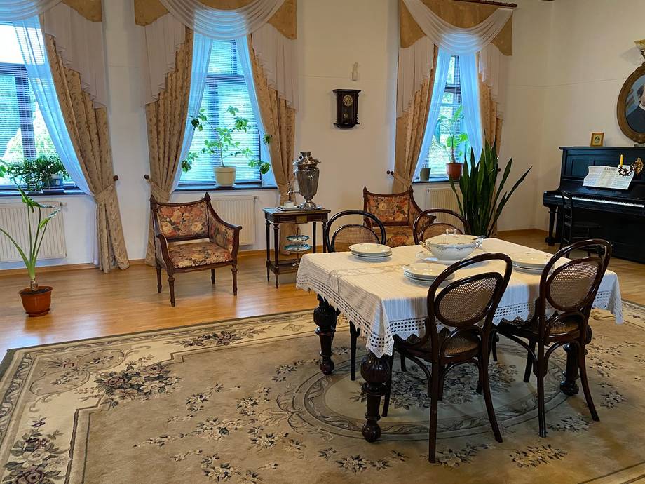 Elegant dining and seating area with period furniture, grand windows, and classical decor