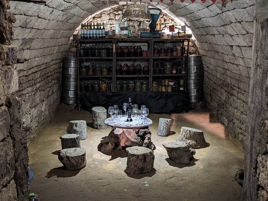 Historic stone cellar with arched ceiling, vintage bar shelving, and rustic wooden seating