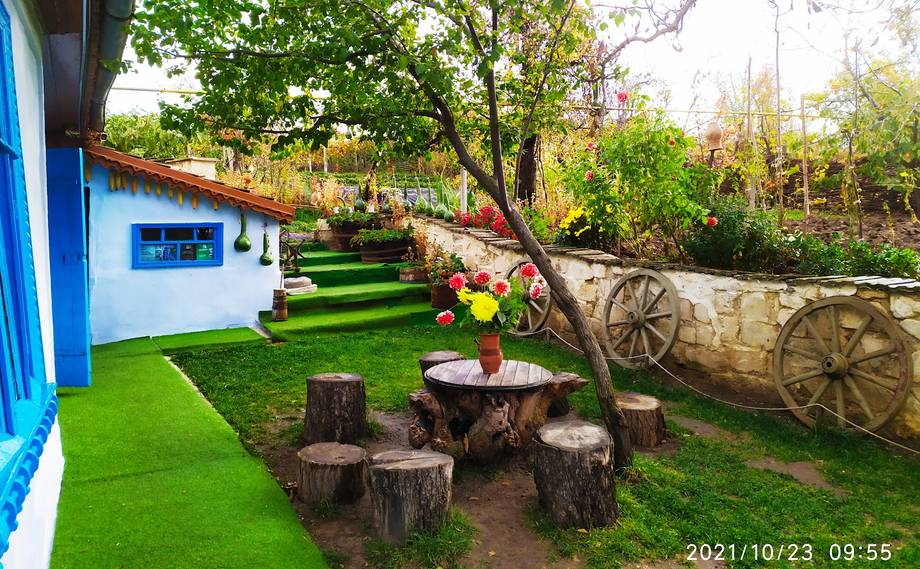 Rustic outdoor terrace with tree-stump seating, vintage wagon, and garden setting