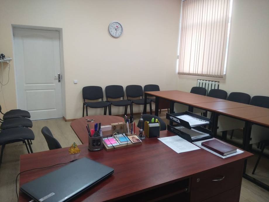 Corporate office meeting room with wooden desks and basic furnishings