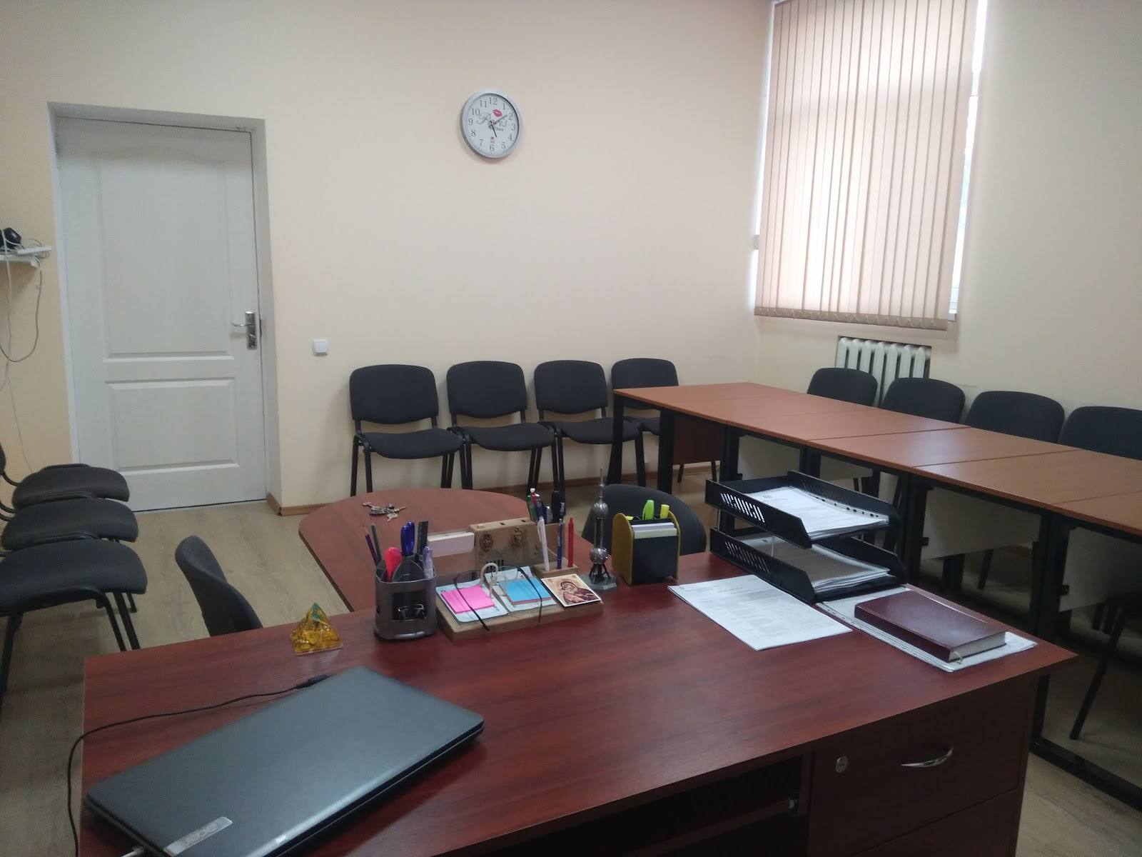 Corporate office meeting room with wooden desks and basic furnishings