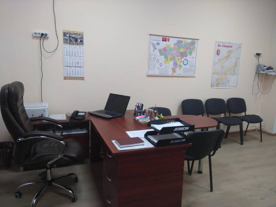 Office workspace with desk, chairs, and wall calendars and maps