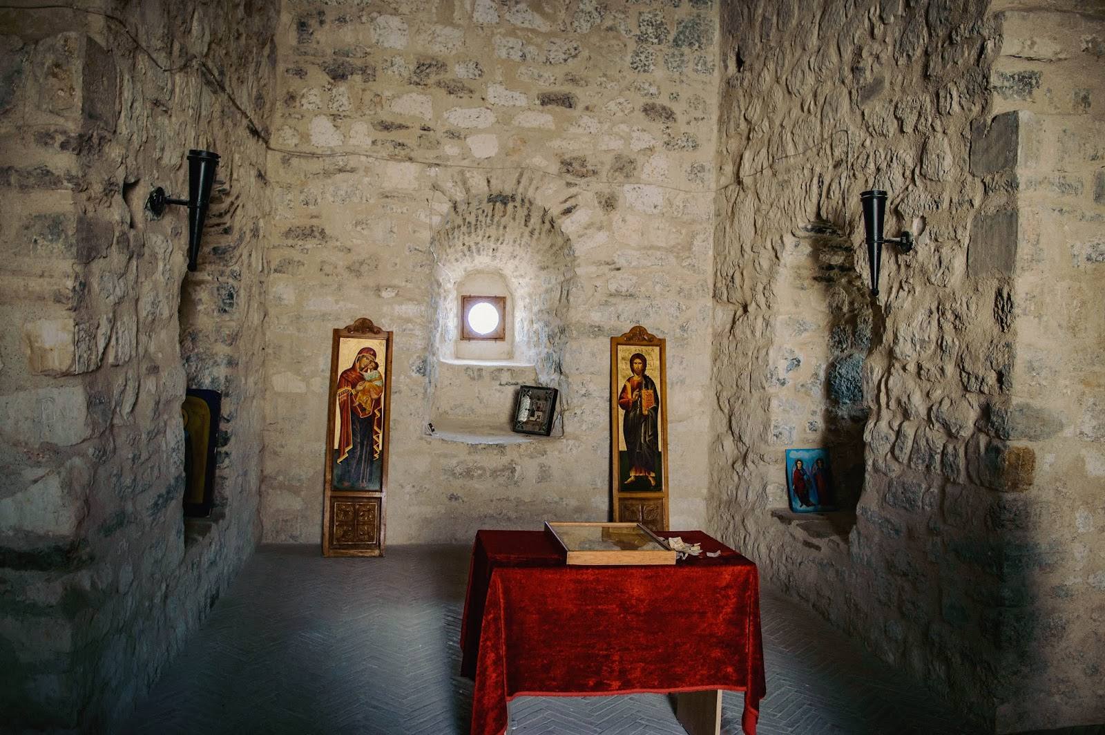 Medieval stone chapel interior with altar, religious icons, and natural light from small window
