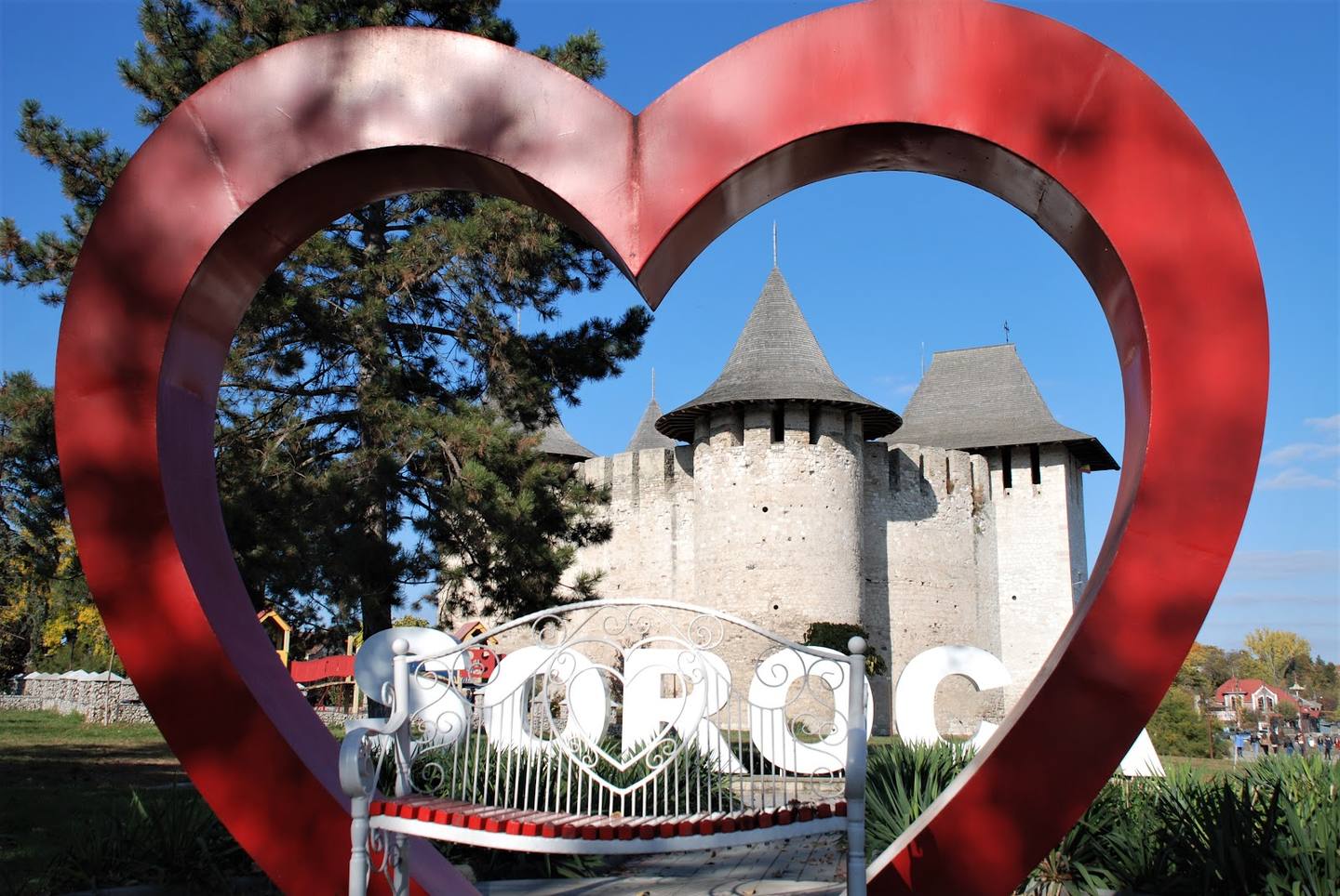 Historic fortress with distinctive medieval towers framed by red heart sculpture