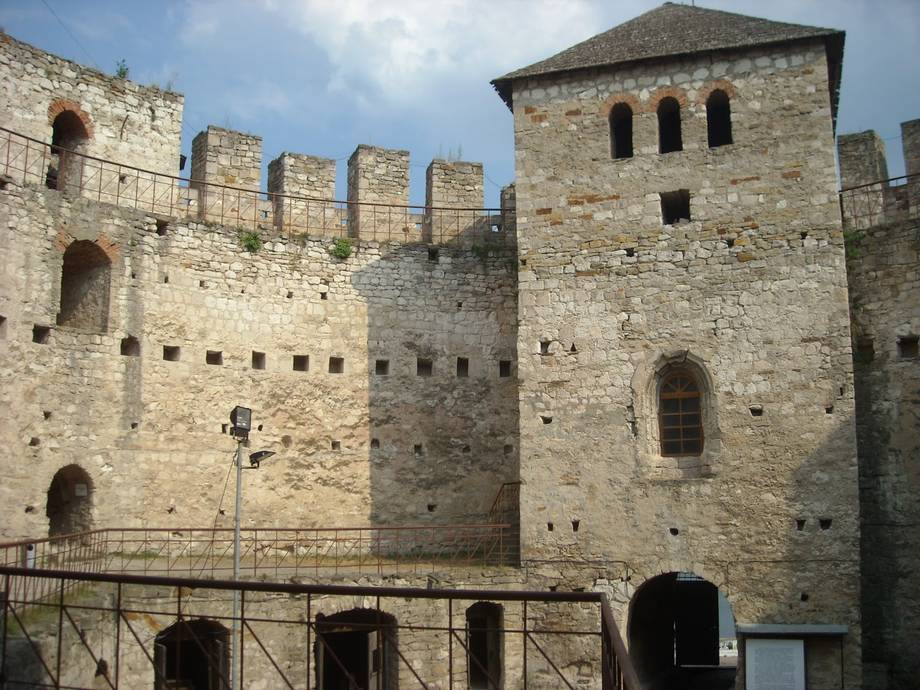 Medieval fortress with stone towers, crenellated walls, and arched windows