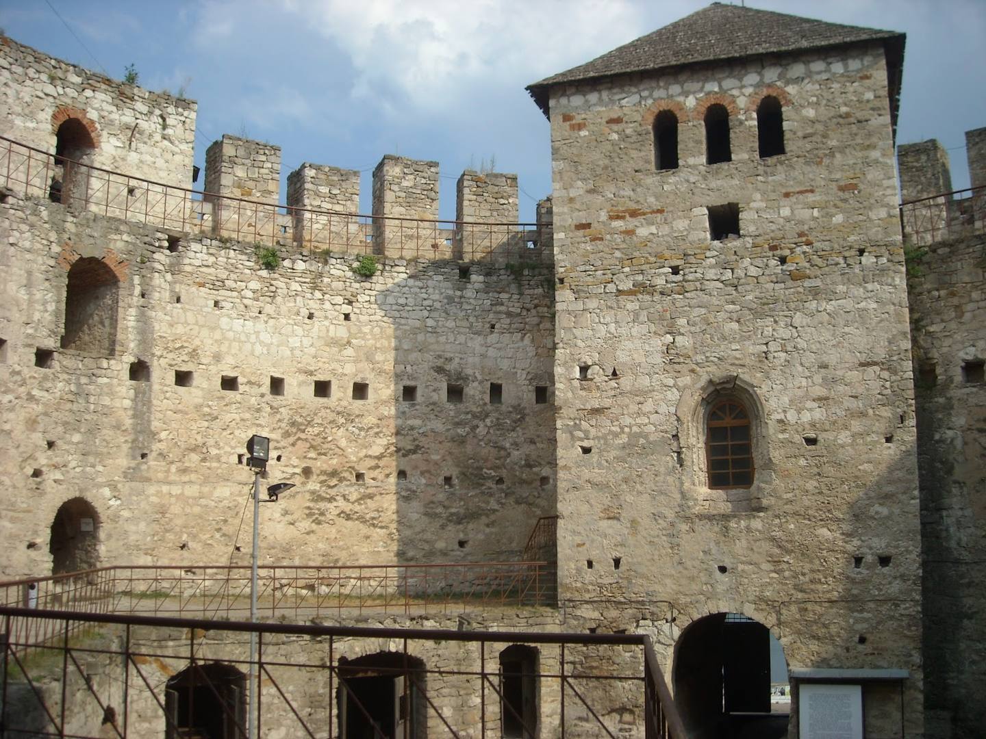 Medieval fortress with stone towers, crenellated walls, and arched windows