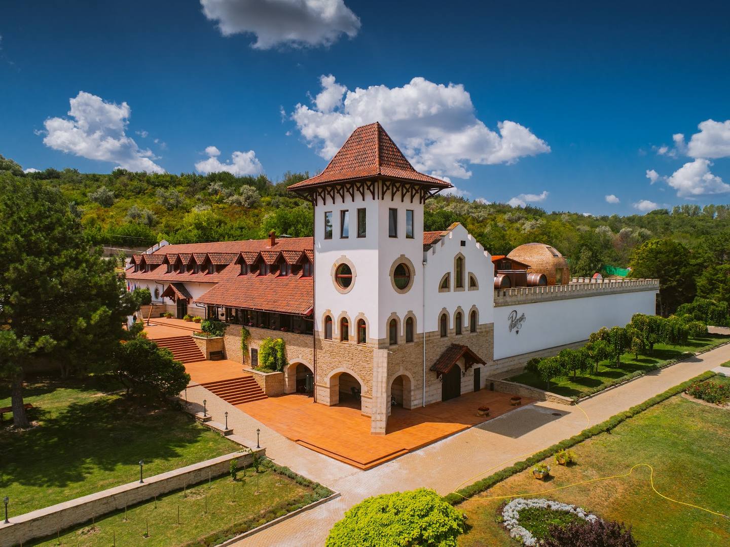 Architectural aerial view of white and terracotta monastery with distinctive tower and manicured grounds
