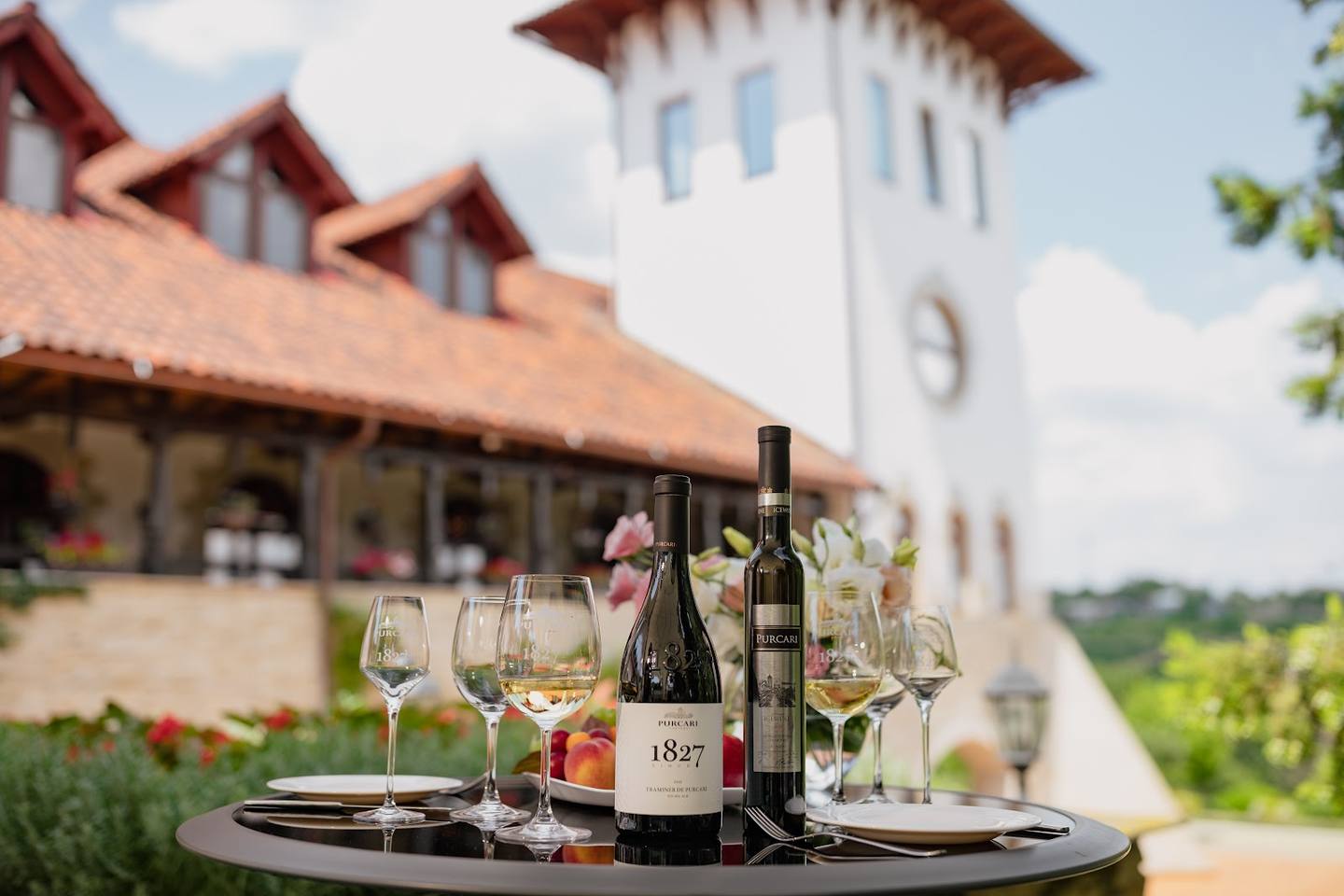 Wine tasting setup with vineyard estate building and tower in background