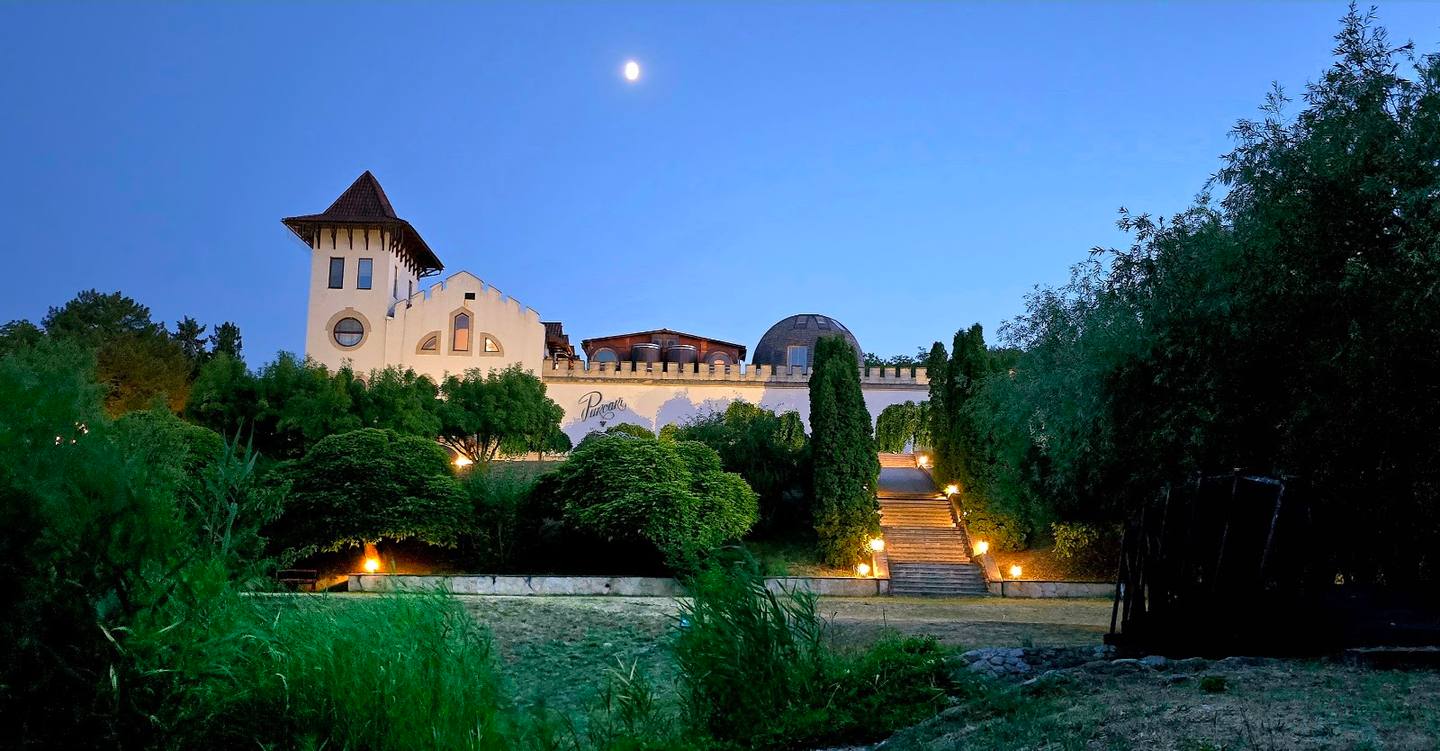 Illuminated fortress estate at dusk with towers and manicured grounds