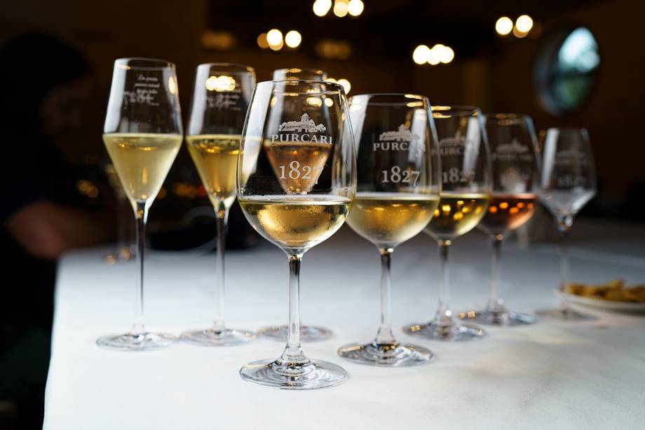 Wine tasting lineup of Purcari wines in branded glasses against blurred bar backdrop
