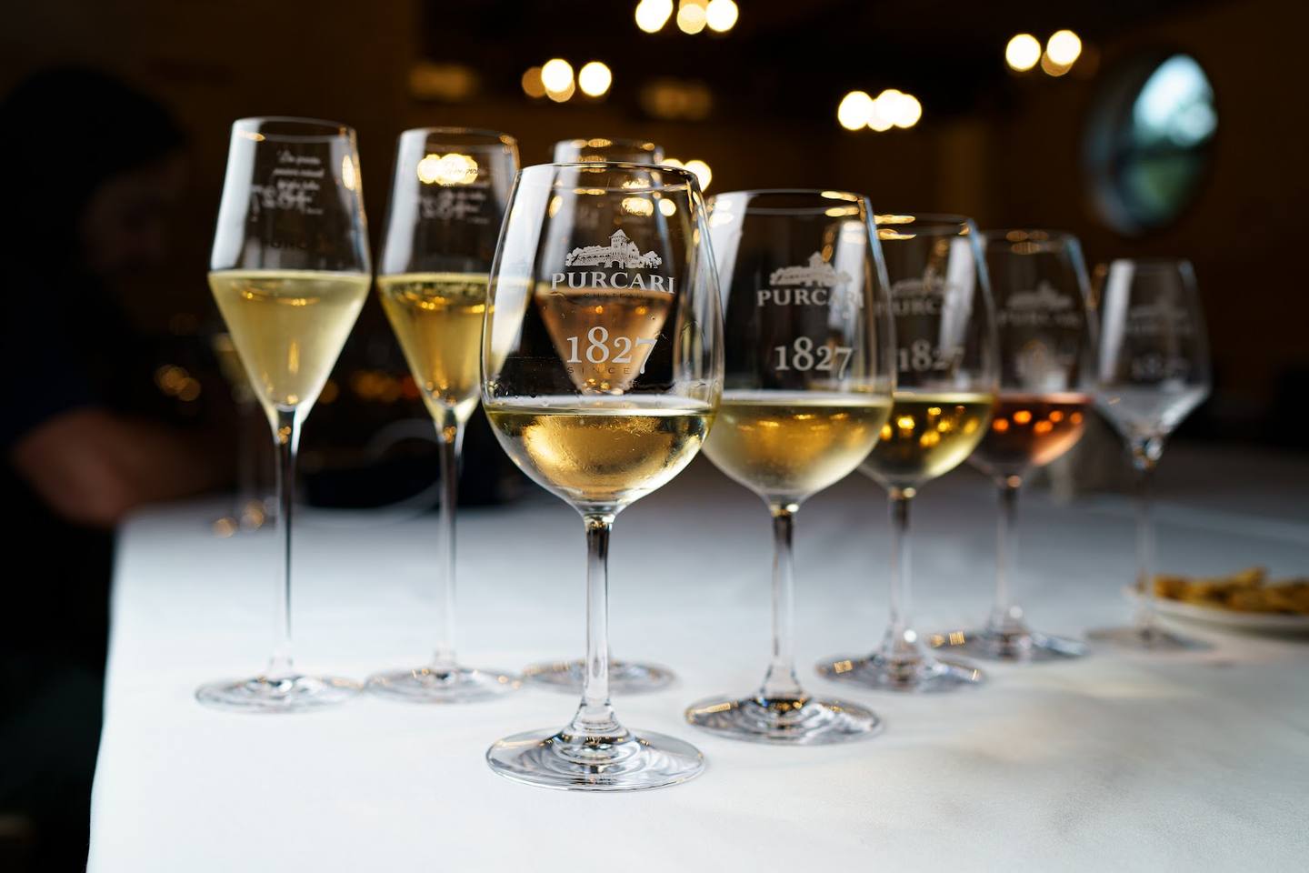 Wine tasting lineup of Purcari wines in branded glasses against blurred bar backdrop