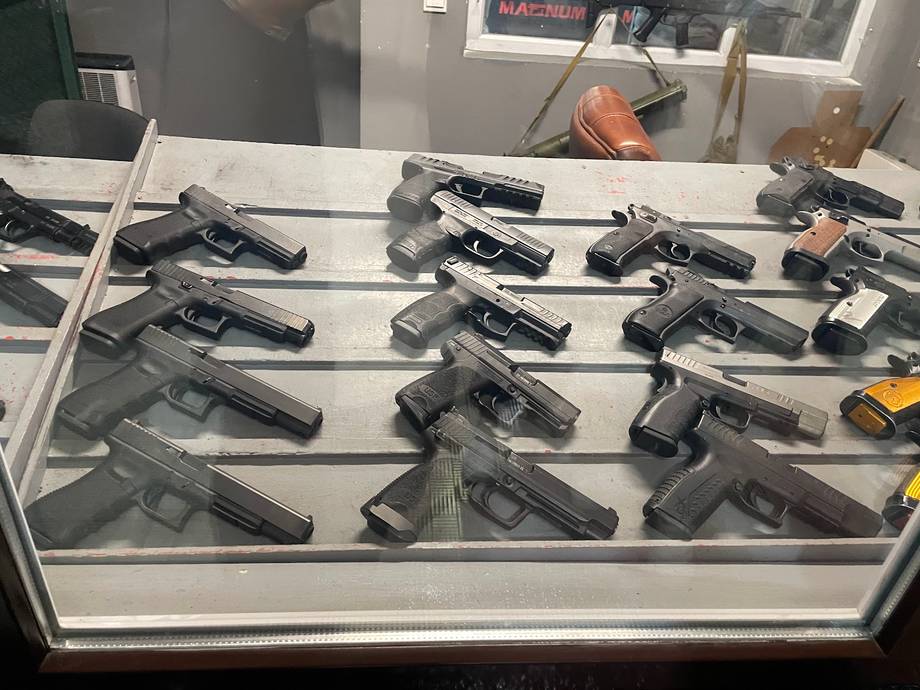 Firearm display case with multiple handguns in glass showcase cabinet