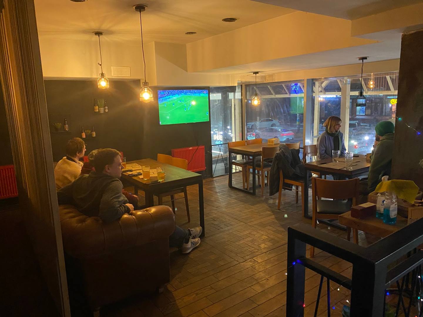 Casual sports bar interior with dining tables, large TV screen, and street-front windows